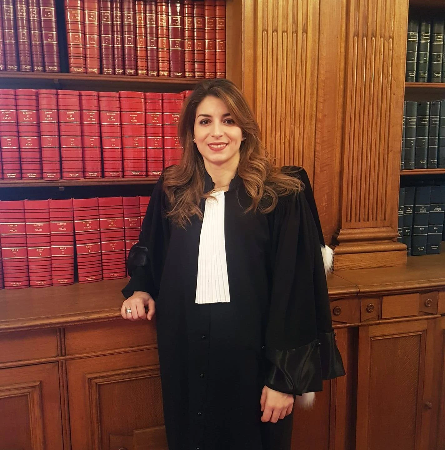 Maître Nadia LALA BOUALI en robe d'avocate devant une bibliothèque juridique